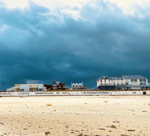 Buildings at beach against cloudy sky