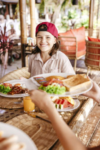 Portrait of smiling girl with breakfast on table in tourist resort during vacation