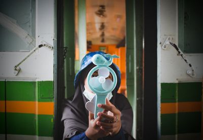 Woman covering face with toy at home