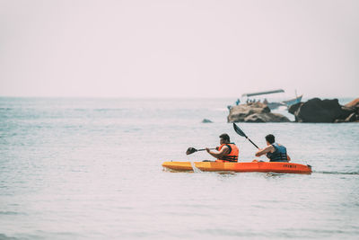 People on boat in sea against clear sky