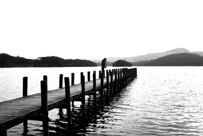 Wooden posts in lake against clear sky