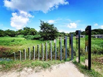 Wooden fence amidst trees on field against sky