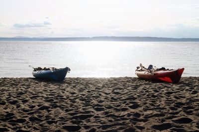 Boat moored on beach against sky