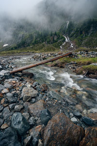 Treee trunk over mountain glaciar melting water river. sulzenau alm, stubai alps, austria