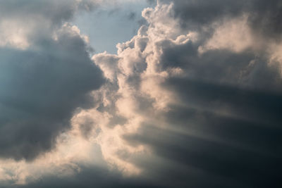 Low angle view of sunlight streaming through clouds