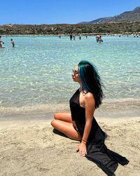 Rear view of woman sitting at beach