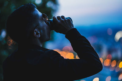 Close-up portrait of man holding camera at night