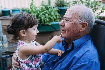 Grandfather and baby girl playing together on the terrace