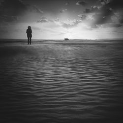 Rear view of silhouette man in sea against sky