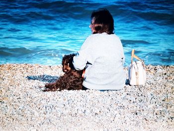 Rear view of woman with dog sitting on beach