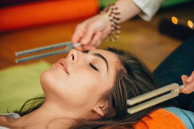 Cropped hands of therapist holding equipment by young woman at spa