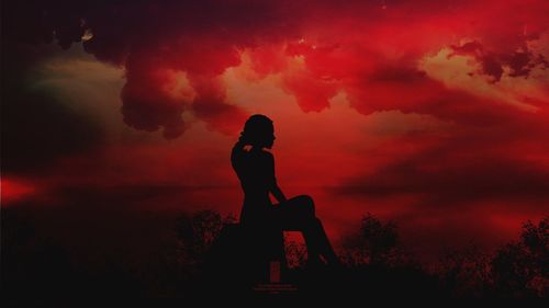 Silhouette woman looking at orange sky