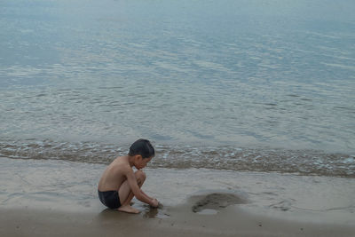 Full length of shirtless boy on beach