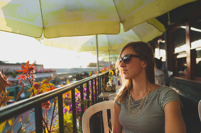 Young woman sitting by railing in restaurant