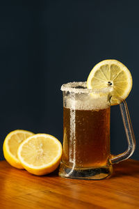 Close-up of lemon slice in glass on table against black background