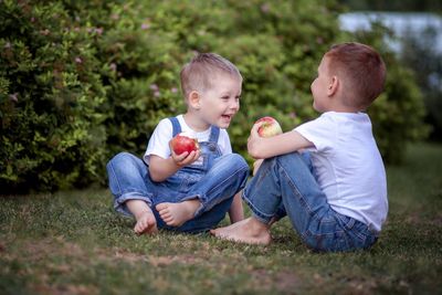 Siblings eating food while sitting outdoors