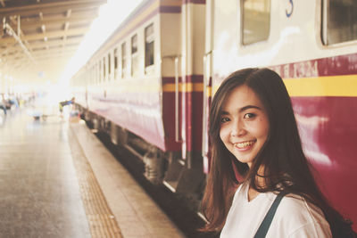 Portrait of young woman standing at railroad station platform