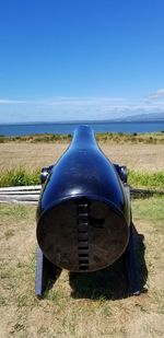 Coin-operated binoculars on field against clear blue sky