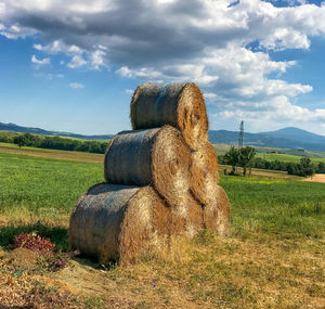 Hay bales on field against sky