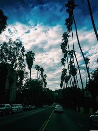 Cars on road against cloudy sky