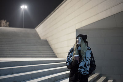 Woman looking away while standing in city at night