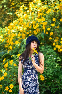 Young woman standing by yellow flowering plants