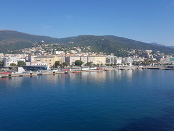 Aerial view of townscape by sea against clear blue sky