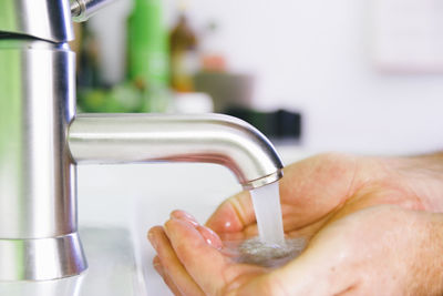 Cropped hands below faucet