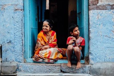 Full length of friends sitting at entrance of building