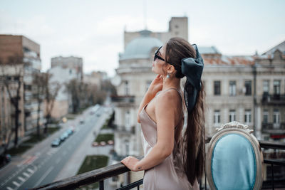 Side view of young woman standing against buildings in city