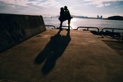 Shadow of man standing on sea shore against sky