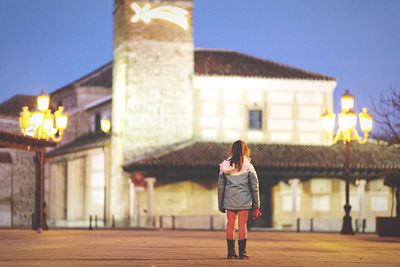 Rear view of girl standing on street in front of historic building