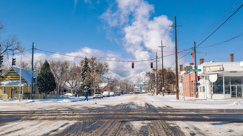 Road by snow covered city against sky