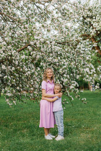 Mom and little daughter are walking through a blooming spring garden