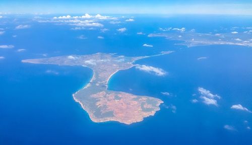 Aerial view of island amidst sea against blue sky