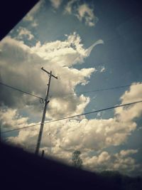 Low angle view of power lines against cloudy sky