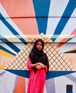 Portrait of young girl standing against wall