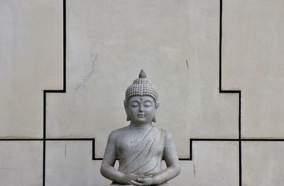 Statue of buddha against wall against building