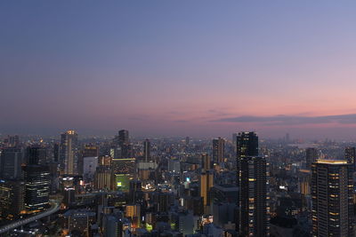 Illuminated buildings in city against sky during sunset
