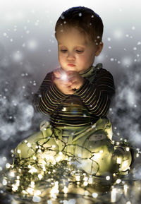 Portrait of cute boy holding illuminated lighting equipment