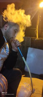 Young man smoking while sitting on table