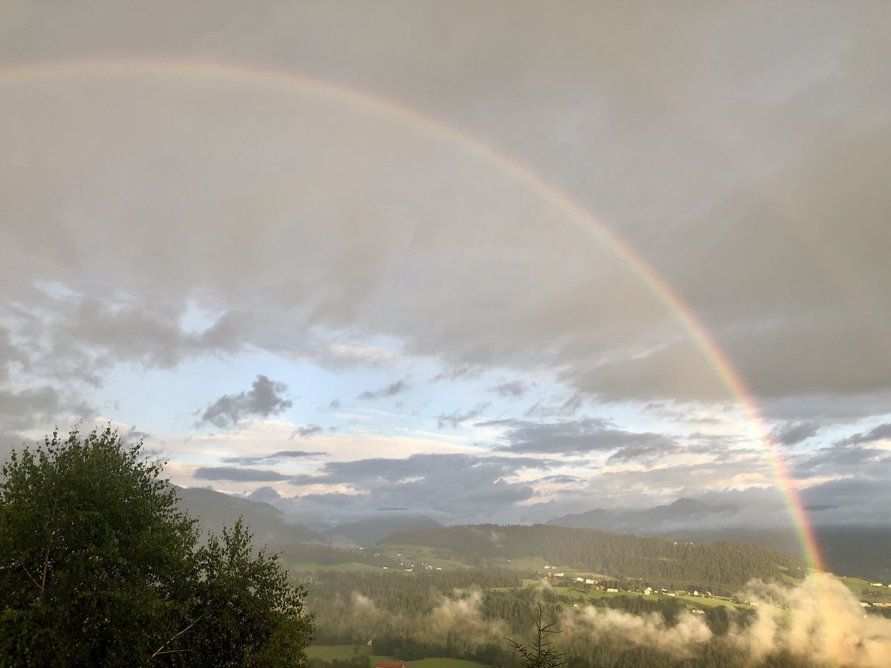 RAINBOW OVER GREEN LANDSCAPE AGAINST SKY