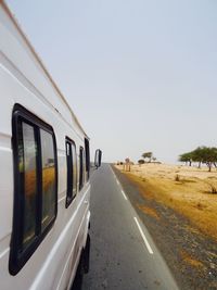 Train moving on road against clear sky