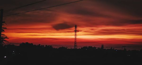 Silhouette of electricity pylon against sky during sunset