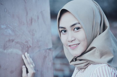 Portrait of woman wearing hijab while standing by wall