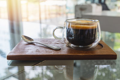 Hot coffee served with a wooden tray on a table.