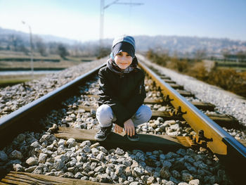 Portrait of boy crouching on railroad track