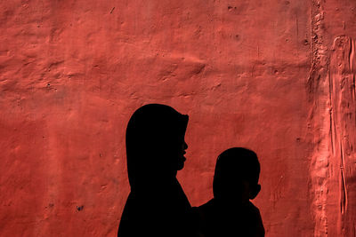 Silhouette people standing against red wall