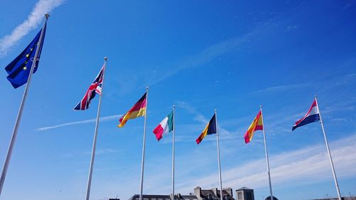 Low angle view of flags against blue sky during sunny day