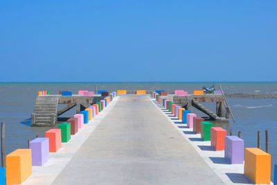 The cement bridge extends into the sea. with colorful barrier panels in the blue sky